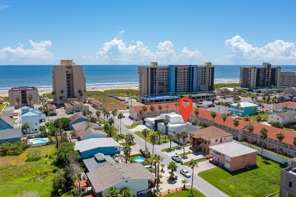 A coastal hotel complex with multiple buildings, a swimming pool, and a view of the beach. - Two Minute Walk to Beach (South Padre Island)