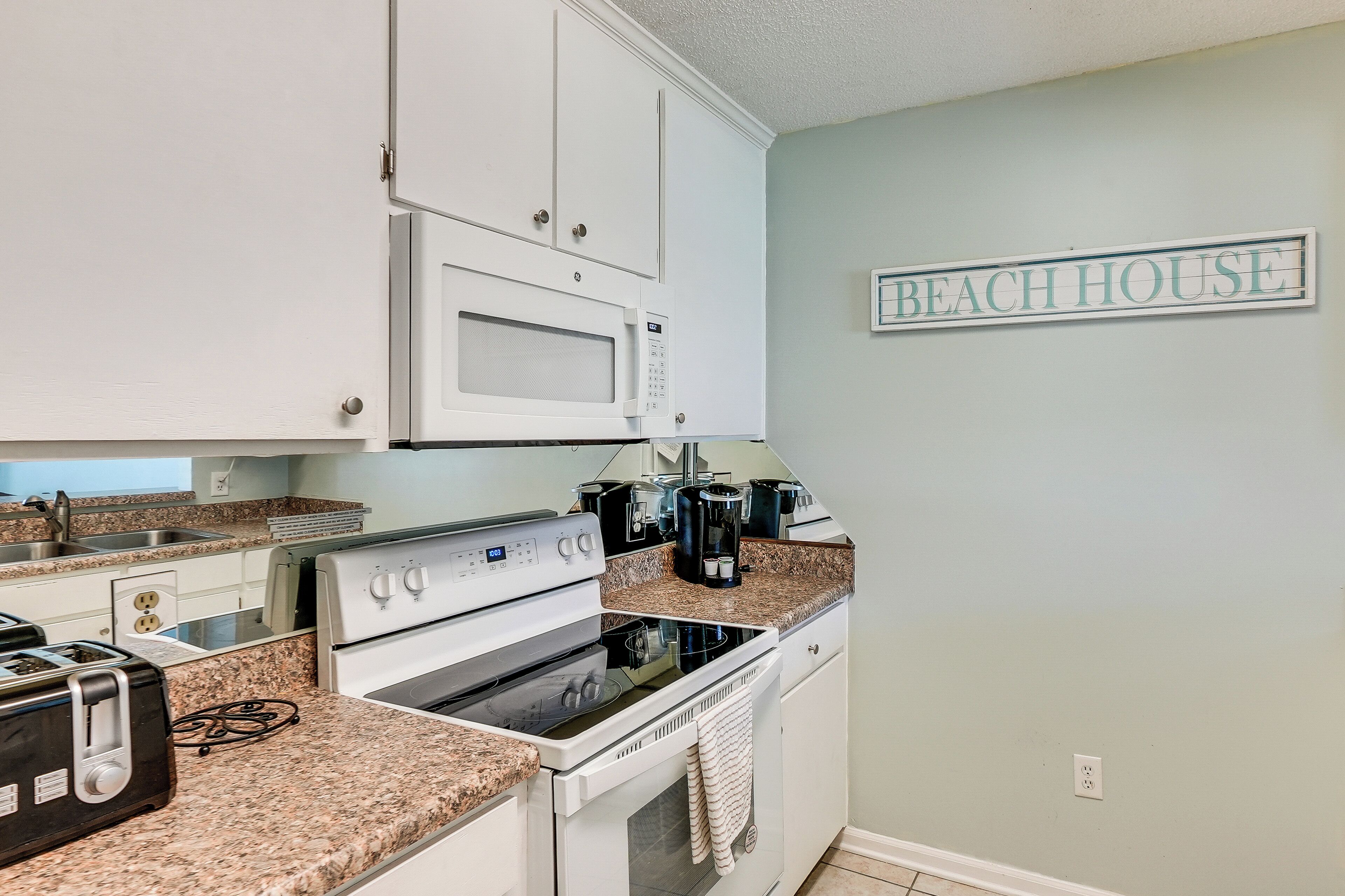 A kitchen with white cabinets, a microwave, a stove, and a coffee maker.