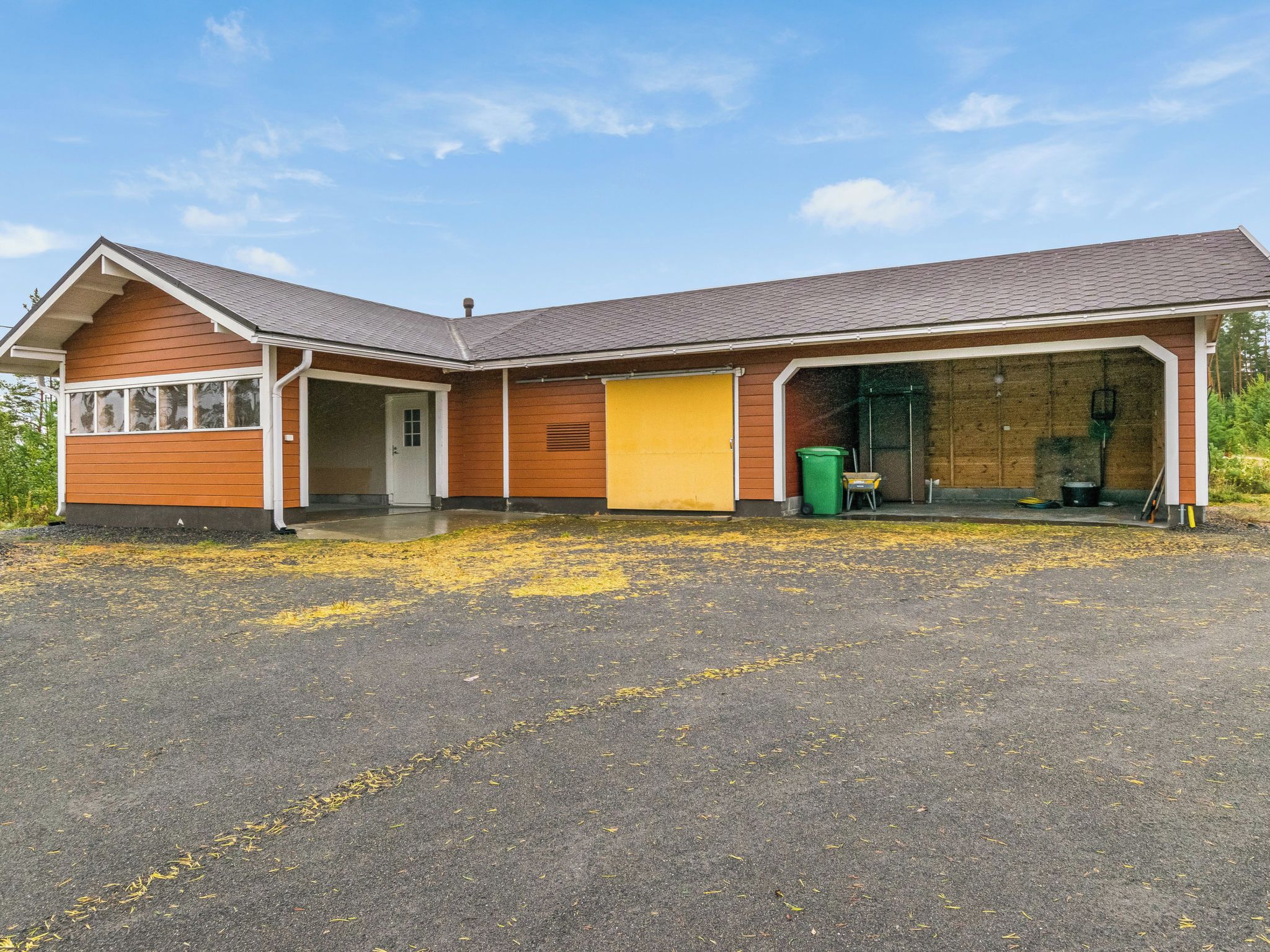 A two-story building with a garage, a front door, and a covered driveway.