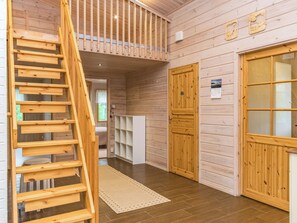 A wooden interior with a wooden staircase, a door with frosted glass panels, and a white shelving unit. - Aurinkoranta by Interhome (Kitee)