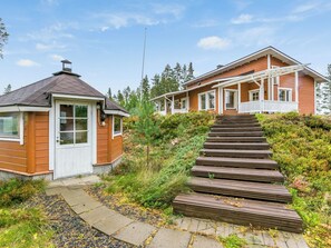 A two-story house with a wooden exterior, a porch, and a staircase leading to the entrance.