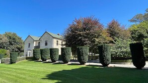 Um gramado bem cuidado com sebes podadas e um edifício de pedra com telhado verde.
