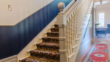 Una escalera con peldaños alfombrados y barandilla blanca ornamentada.