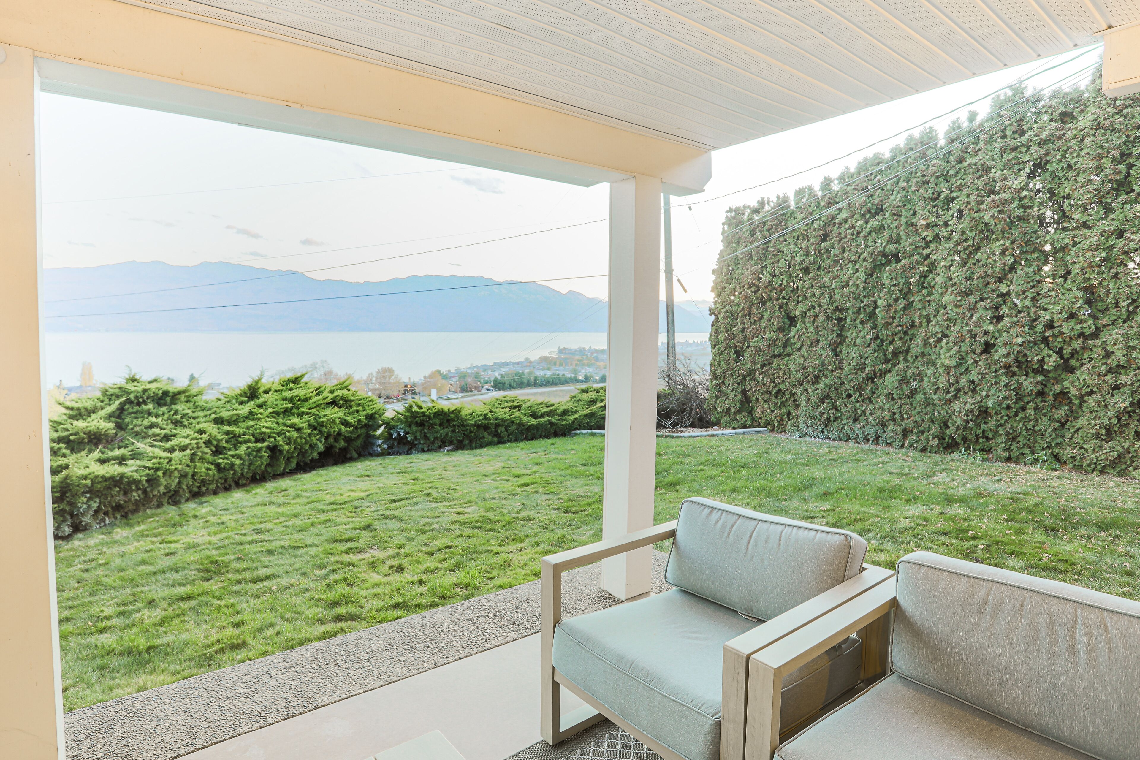 A covered outdoor seating area with a view of a lake and mountains.