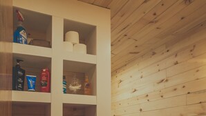 Une salle de bain avec des murs en bois, un lavabo blanc et un porte-serviettes avec des serviettes jaunes et blanches.
