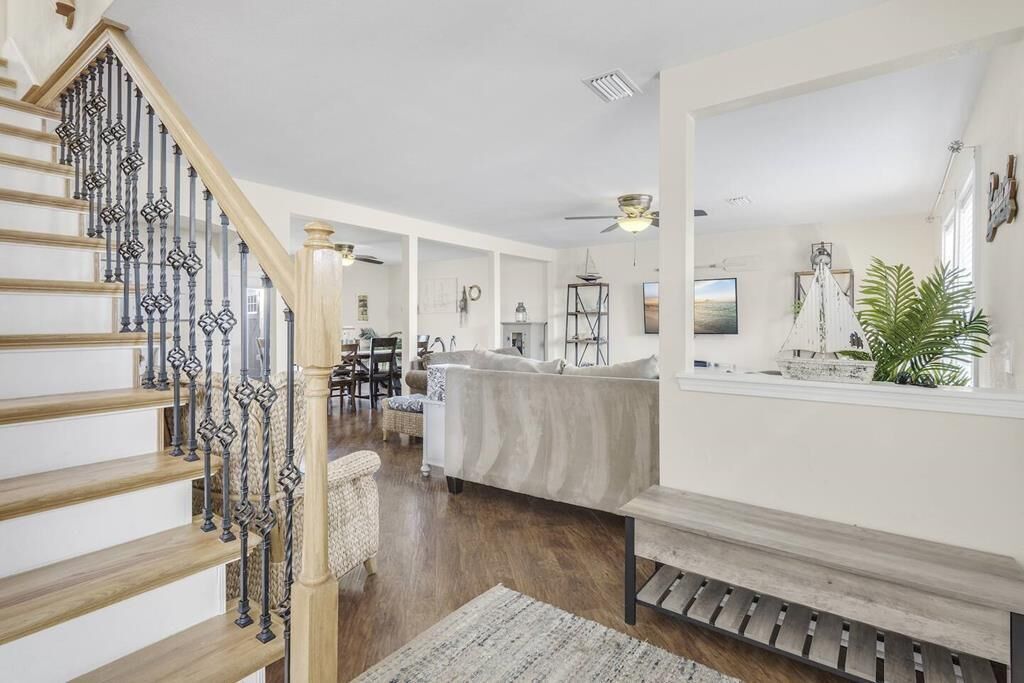 A spacious living area with a staircase, a sofa, a coffee table, and a dining table.