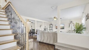 A spacious living area with a staircase, a sofa, a coffee table, and a dining table.