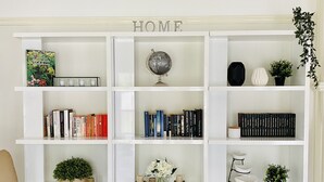 Une bibliothèque blanche avec des livres, un globe terrestre et des objets décoratifs.