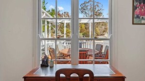 Une pièce dotée d’une grande fenêtre donnant sur une terrasse aménagée avec du mobilier d’extérieur.