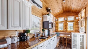 A modern kitchen with white cabinetry, a wooden countertop, and a built-in stove.