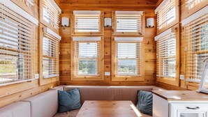 A cozy cabin interior with a wooden interior, a bench seating area, and a table.