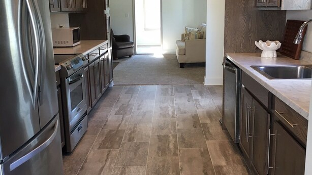 Una cocina moderna con electrodomésticos de acero inoxidable, armarios de madera oscura y suelo de baldosas.