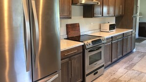 Una cocina moderna con electrodomésticos de acero inoxidable, armarios de madera y suelo de baldosas.
