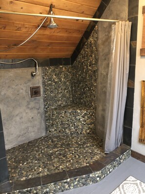 Dusche mit einer Wand aus Kieselmoos, Holzboden und einer Duschvorhang.