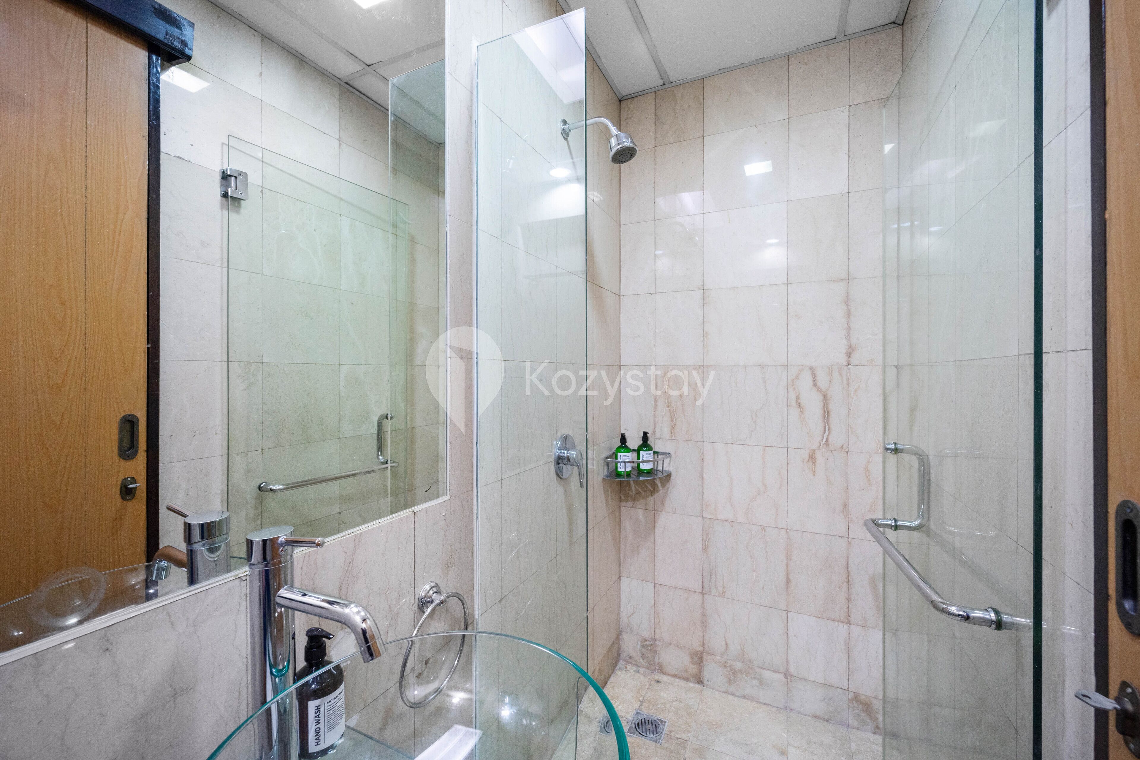 Un baño moderno con cabina de ducha de vidrio, lavamanos de vidrio y tocador con espejo.