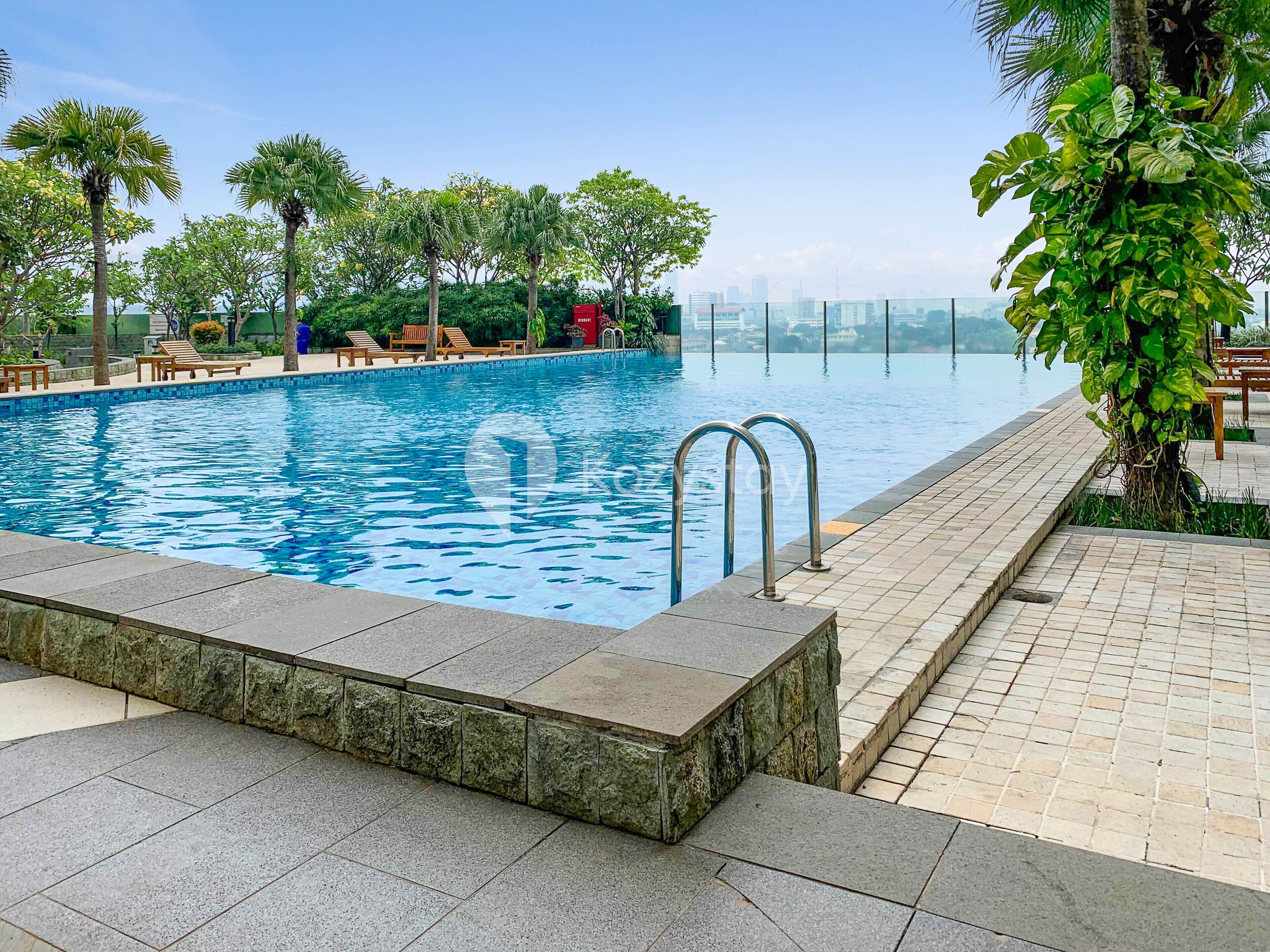Ein Swimmingpool mit klarem, blauem Wasser, umgeben von Liegestühlen und Palmen.