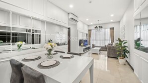 A modern kitchen with white cabinetry, a dining table set for four, and a large window with curtains. - CASTILLE by Kozystay (Jakarta)