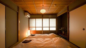 A traditional Japanese room with tatami flooring, a sliding door, a window with shoji screens, and a hanging paper lantern.