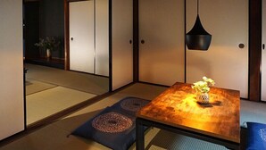 A traditional Japanese room with tatami flooring, a low table with a vase, and sliding doors.