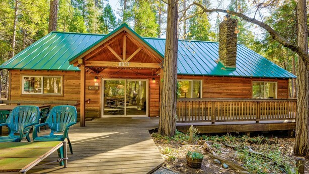 Une cabane en bois avec un toit vert, une véranda avec des chaises et une plaque portant le numéro « 8037 ».