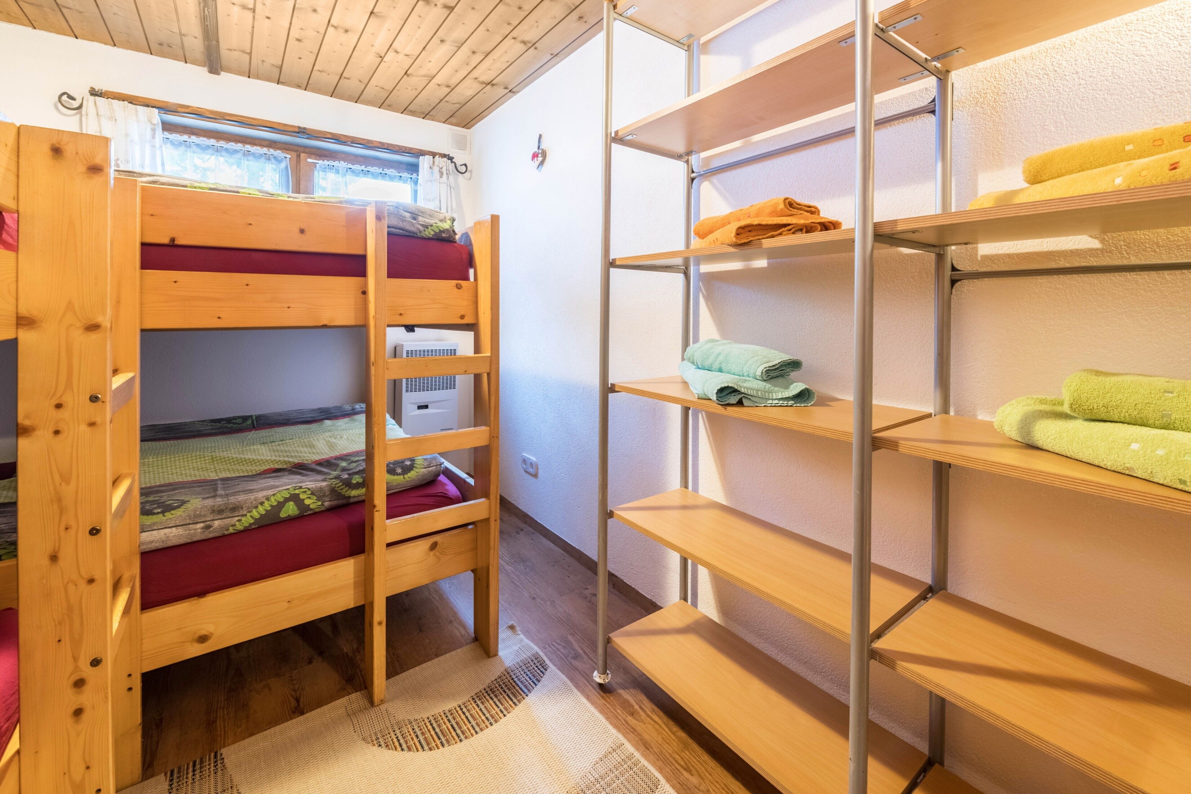 A bunk bed room with a metal shelving unit against the wall.