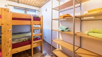 A bunk bed room with a metal shelving unit against the wall.