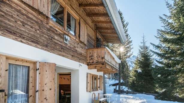 Eine Holzhütte mit Balkon, einer Tür und einem Fenster.