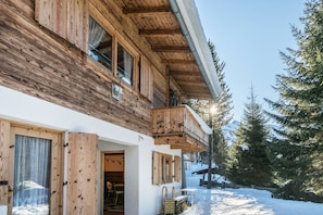 A wooden cabin with a balcony, a door, and a window.