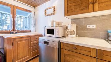 A compact kitchen with wooden cabinets, a dishwasher, a microwave, and a coffee maker.