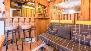 Ein Holzinterieur mit einer Couch, zwei Barhocker, einem Spiegel und einem Gemälde an der Wand.