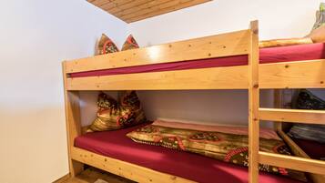 A bunk bed with red bedding and decorative pillows.