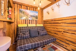 A wooden cabin interior with a sofa, a painting, and antlers on the wall.
