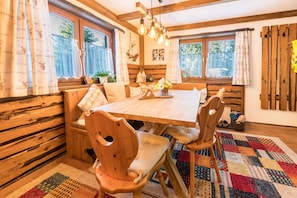 A wooden dining table with chairs, a bench, and a colorful rug.