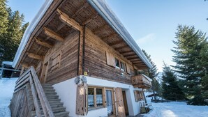 Eine Holzhütte mit Treppe, einer überdachten Veranda und verschneitem Gelände.
