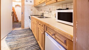 A kitchen with wooden cabinets, a microwave, a sink, and a stove. - Hochfügenblick - Relaxation for Two (Hochfügen)