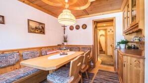 A wooden dining area with benches and chairs, a chandelier, and a view into a hallway. - Hochfügenblick - Relaxation for Two (Hochfügen)