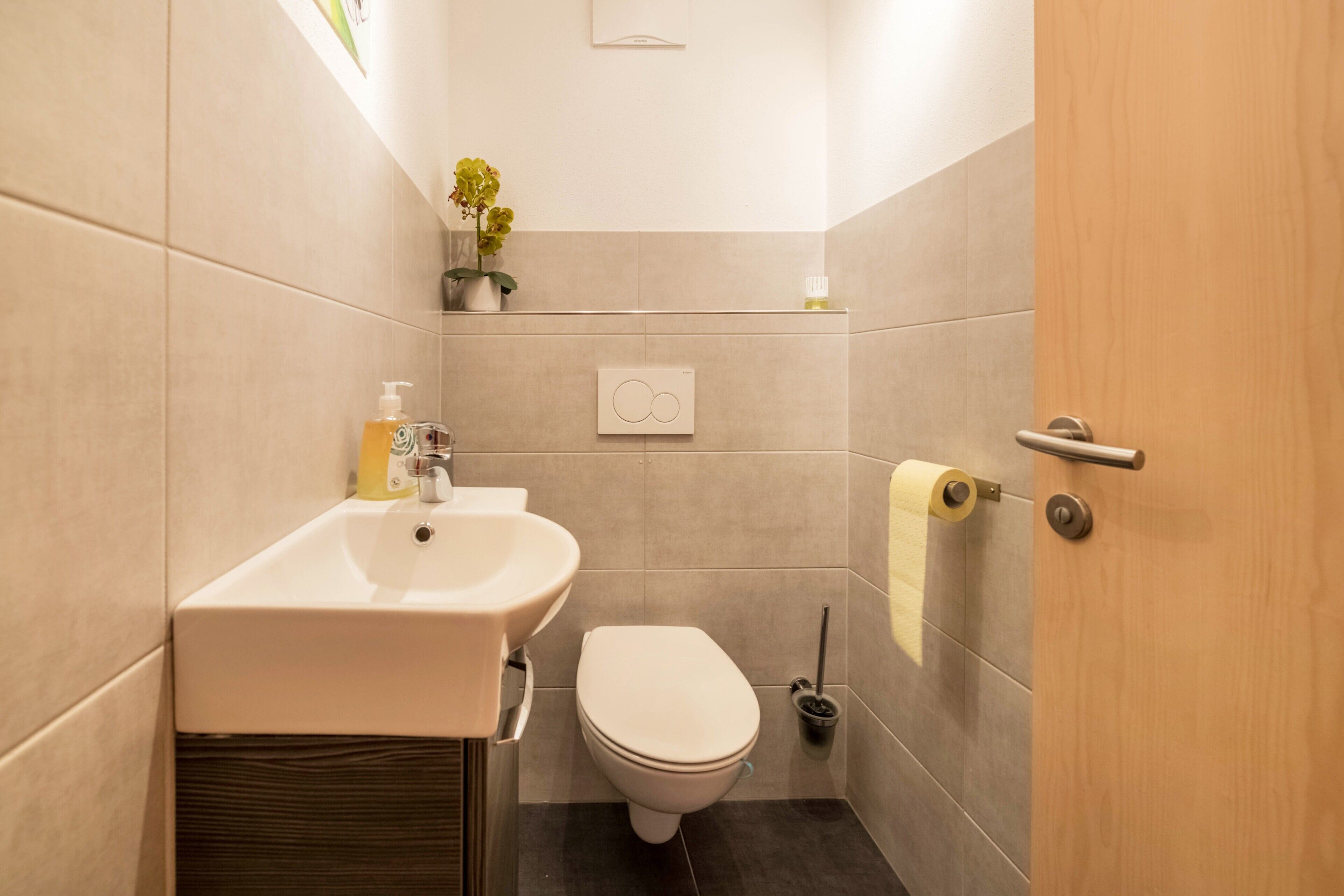 A bathroom with a sink, toilet, and a toilet paper holder.