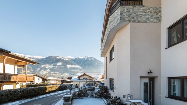 Ein Gebäude mit einer Steinaußenwand, einem Balkon und Blick auf schneebedeckte Berge.