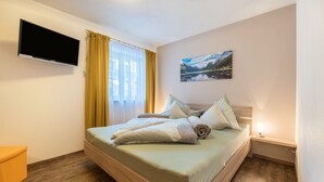Ein Hotelzimmer mit Bett, Wandfernseher, Gemälde und Nachttischlampe.