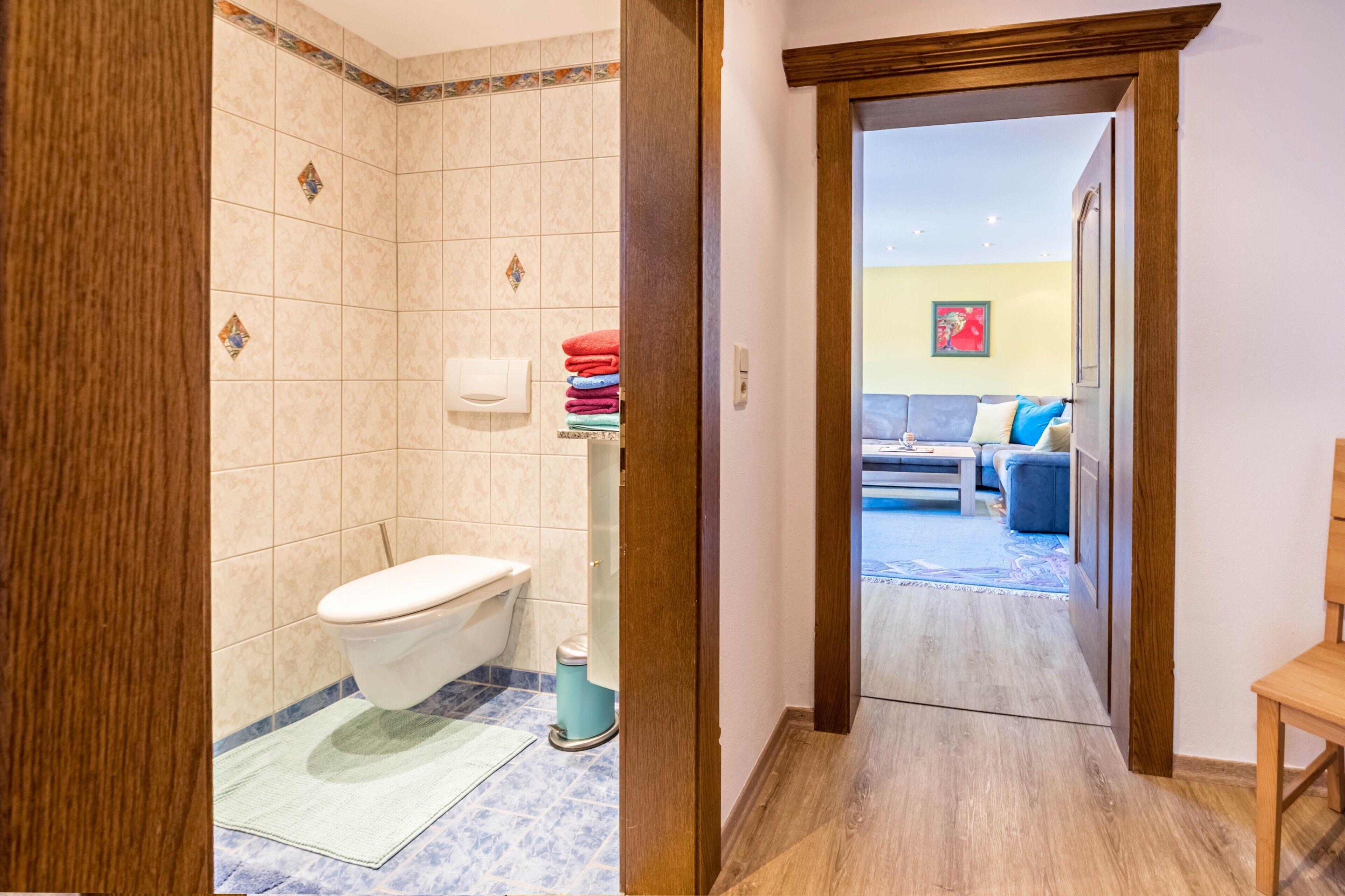Ein Badezimmer mit Toilette, einem Handtrockner und einem Handtuchhalter mit gefalteten Handtüchern.