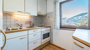 A kitchen with white cabinets, a wooden countertop, a stainless steel sink, and an oven. - Wieseneck II - Apartment in Fügen (Fügen)