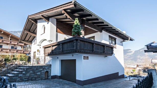 A white building with a wooden balcony and a stone staircase. - Wieseneck II - Apartment in Fügen (Fügen)