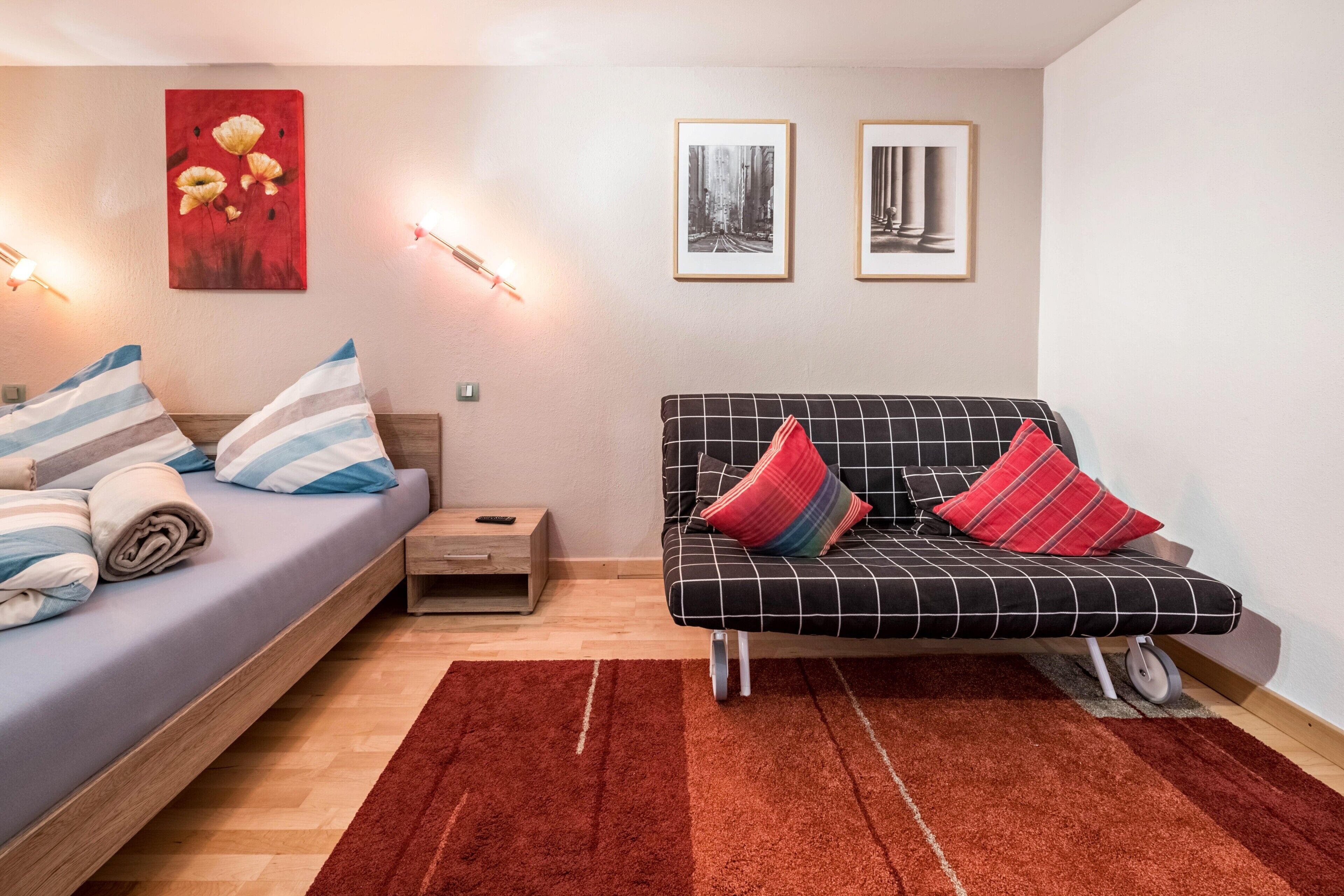 A modern room with a bed, sofa, and artwork on the walls.