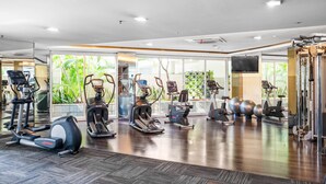 A gym with various exercise equipment, large windows, and a polished wooden floor. - CLASSICO by Kozystay (Jakarta)