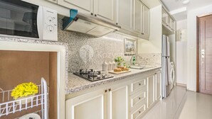 A modern kitchen with a granite countertop, stainless steel appliances, and a built-in microwave. - CLASSICO by Kozystay (Jakarta)