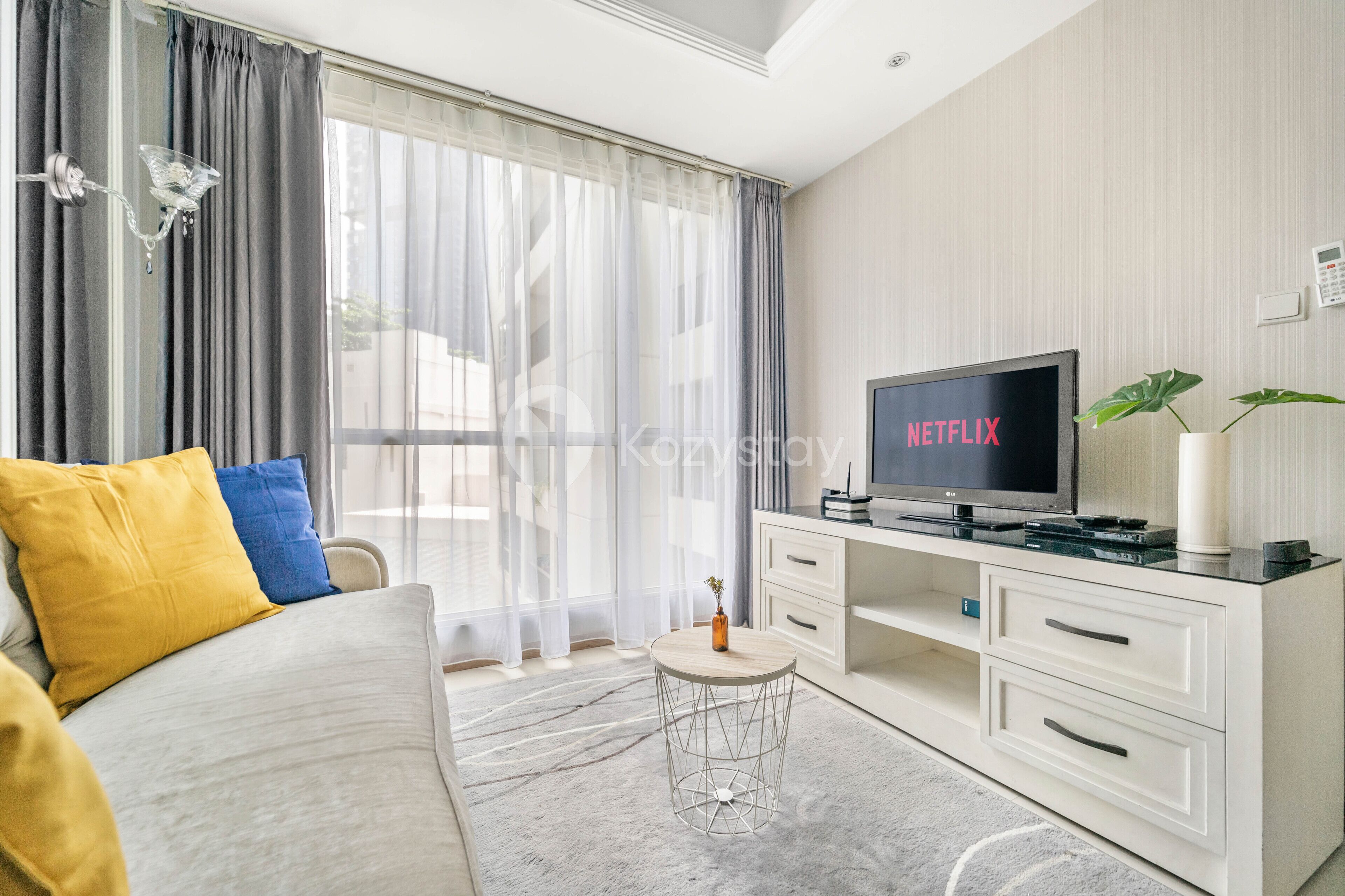 A modern hotel room with a large bed, a TV, a small side table, and a white dresser.