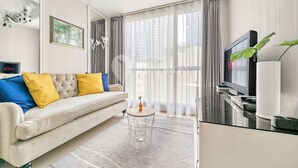 A modern living room with a sofa, a coffee table, a TV, and a large window with curtains. - CLASSICO by Kozystay (Jakarta)