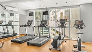 Un gimnasio con cintas de correr, elípticas y una bicicleta estática.