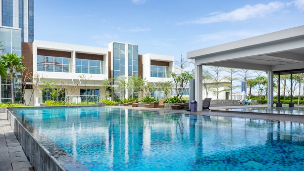 Un hotel moderno con una amplia piscina cubierta, zonas de estar al aire libre y vistas de los edificios circundantes.
