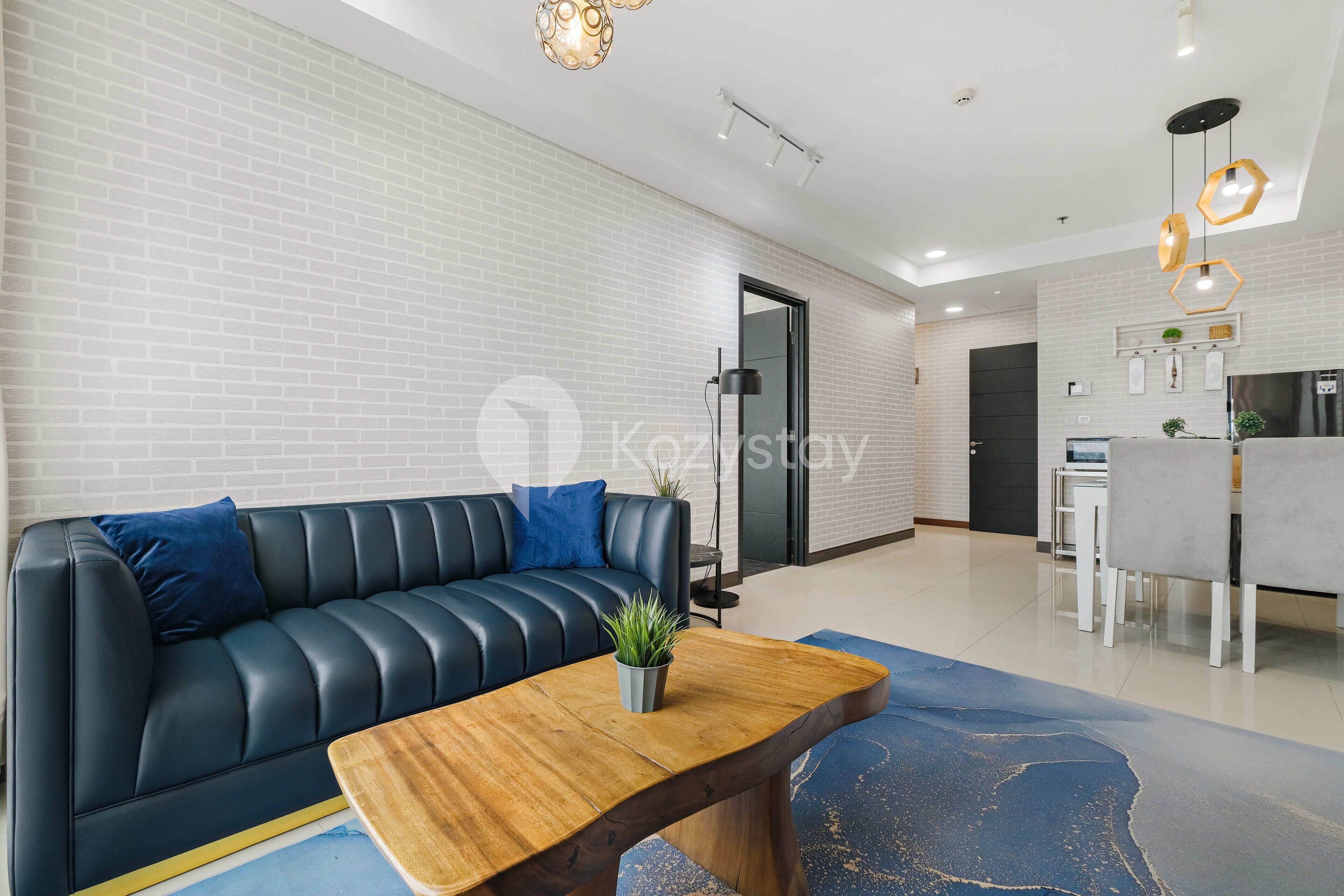 Una sala de estar moderna con un sofá de cuero negro, una mesa de centro de madera y una alfombra azul.